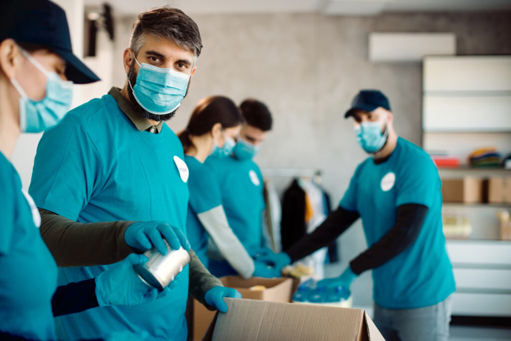 Group of people with protective face masks packing donation boxe